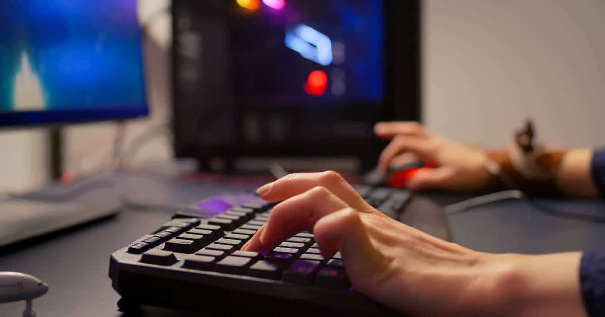 Which Version of Windows is Best for Gaming, Person Playing a Game on PC, Close-up of Their Hands on a Keyboard